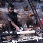 A carpenter preparing part of a kitchen item (rolling pin) at his workplace