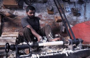 A carpenter preparing part of a kitchen item (rolling pin) at his workplace