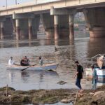 Youngsters waiting for tourists while sitting on their boat at Ravi River bank during evening time