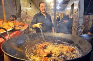 A vendor roasting chicken for customers at Hashtnagri area