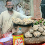 A vendor selling food item Shakar Khandi at his road side setup.