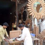 Workers are busy in carving design on the wooden sheet at their workplace