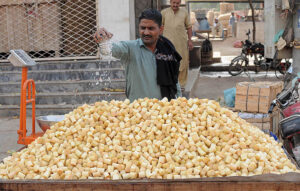 A vendor is busy sprinkling water on the pieces of sugarcane to keep them fresh at his handcart