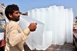 A laborer busy in unloading ice block from a delivery rickshaw at his roadside setup in the city.