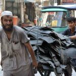 Laborers punching hand cart loaded with scrap leader for recycling purpose at Namak Mandi Chowk.