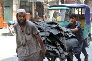 Laborers punching hand cart loaded with scrap leader for recycling purpose at Namak Mandi Chowk.