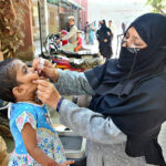 Health worker administering polio vaccine drops to a child during a Polio vaccination campaign at Government Hospital at Norani basti.