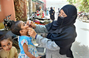 Health worker administering polio vaccine drops to a child during a Polio vaccination campaign at Government Hospital at Norani basti.