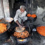 An elderly vendor preparing traditional sweet item at Waleed Mohallah.