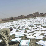 A worker drying washed plastic bags under the sun at his workplace