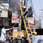 Staff of MEPCO fixing electricity fault on a tower at roadside in the city