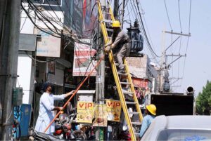 Staff of MEPCO fixing electricity fault on a tower at roadside in the city