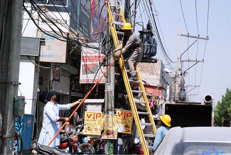 Staff of MEPCO fixing electricity fault on a tower at roadside in the city