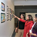 Students of National College of Arts viewing the displayed artwork during an exhibition in the college