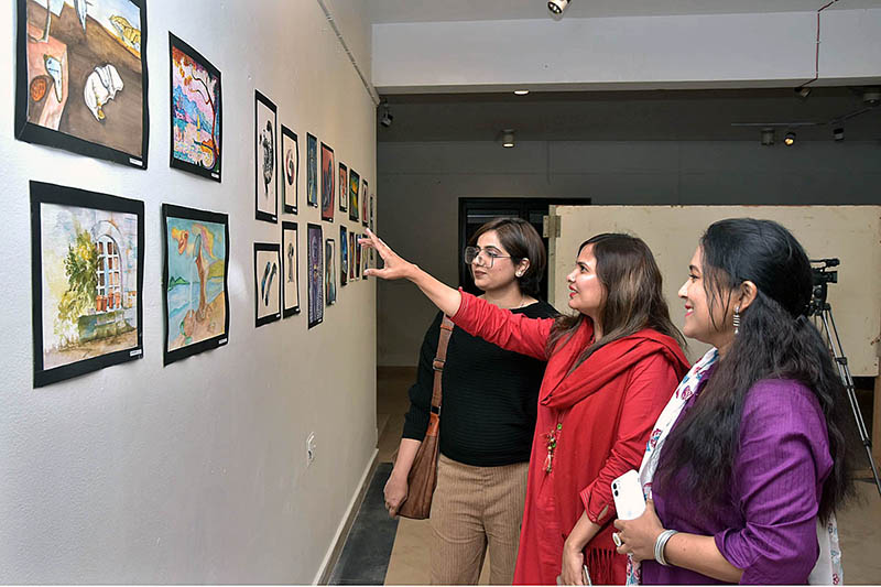 Students of National College of Arts viewing the displayed artwork during an exhibition in the college