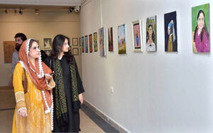 Students of National College of Arts viewing the displayed artwork during an exhibition in the college