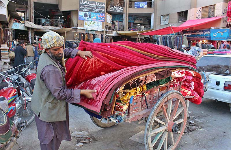 Worker busy to shift blankets in his shops at Meezan Chowk.