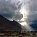 An attractive view of sun rays peeping from the clouds during dark clouds hovering over the city
