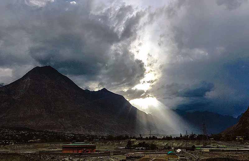 An attractive view of sun rays peeping from the clouds during dark clouds hovering over the city