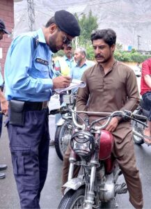 A traffic police official issuing challan to a motorcyclist on violation of not wearing helmet during city traffic police campaign "Hakmet Nai Tou Saffer Nahi"