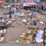 People busy in selecting and purchasing old shoes from vendor along expressway