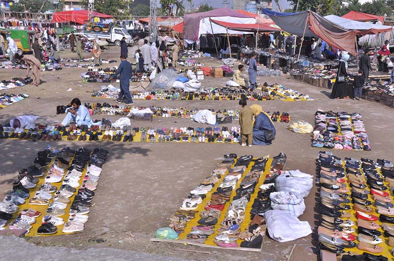 People busy in selecting and purchasing old shoes from vendor along expressway