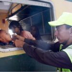 Health worker administering polio drops to a child in train at Cantt Station