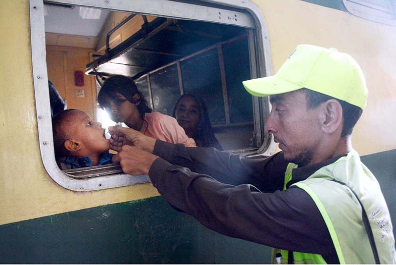 Health worker administering polio drops to a child in train at Cantt Station