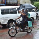 A motorcyclist on his way under the cover of Umbrella during rain