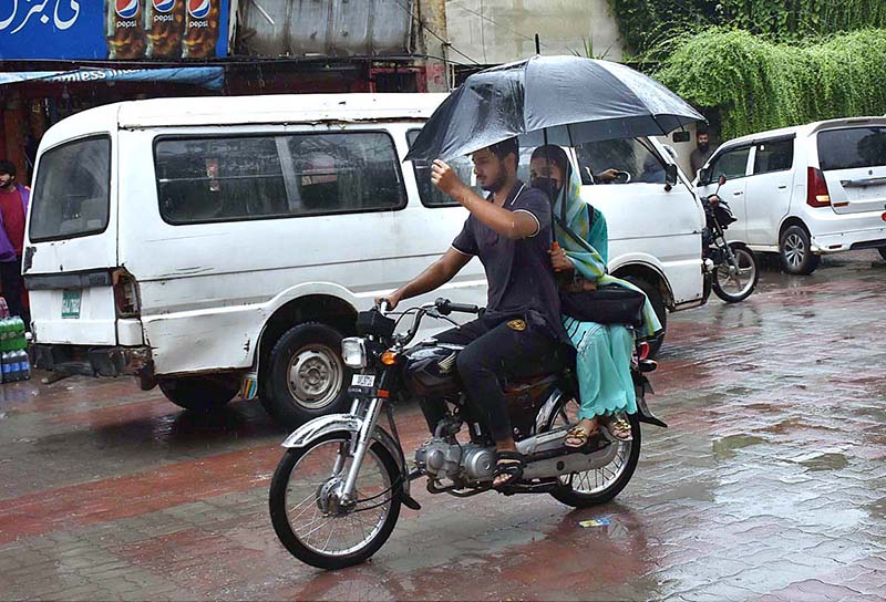 A motorcyclist on his way under the cover of Umbrella during rain