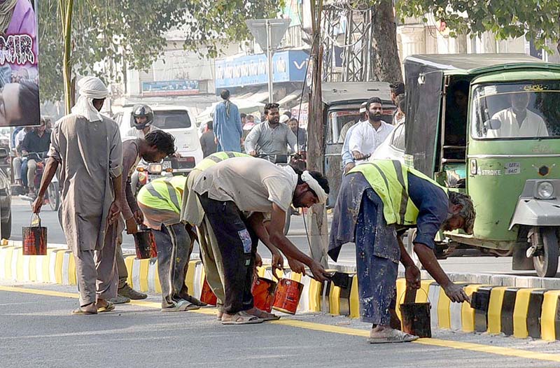 Workers busy in painting the footpath at Mall Road