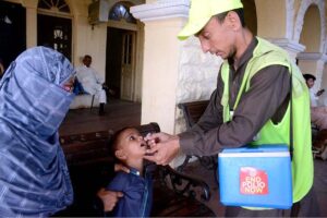 Health worker administering polio drops to a child in train at Cantt Station