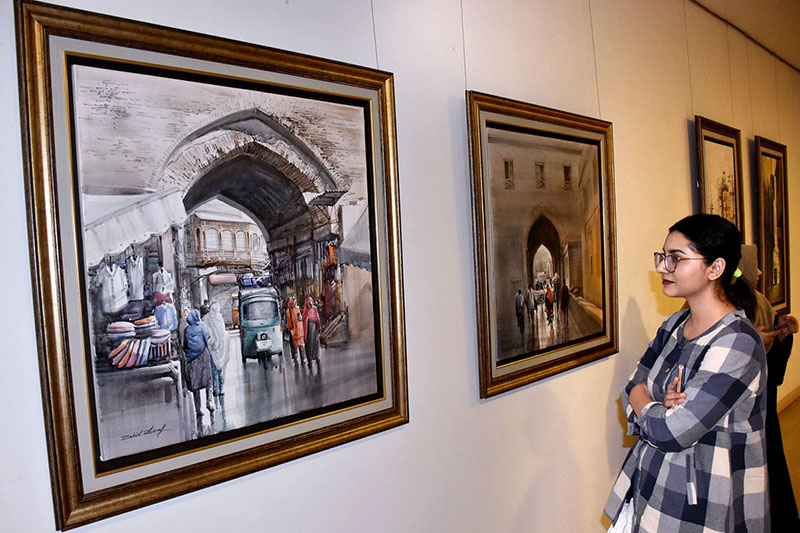 Female Visitor keenly viewing painting during the painting exhibition “Lahore Lahore hai” by Zahid Ashraf at Ejaz Art Gallery