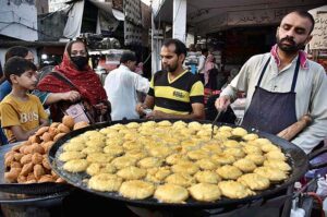 A vendor is busy in making and selling the traditional food item “Laddu Peethi” to the customers at outside Dehli Gate.