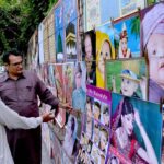 An elderly man is decorating printed pictures on the wall to earn a living for children in the city