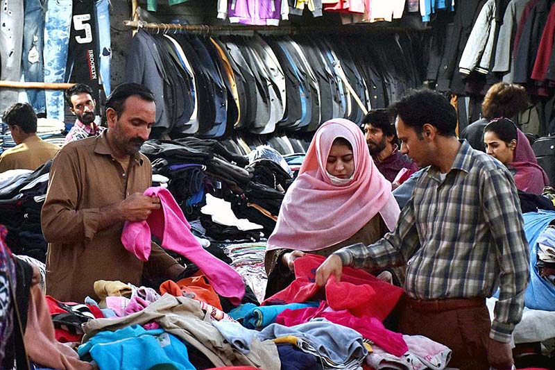 A lady selecting and purchasing second hand shoes at a vendors setup in Landa Bazar