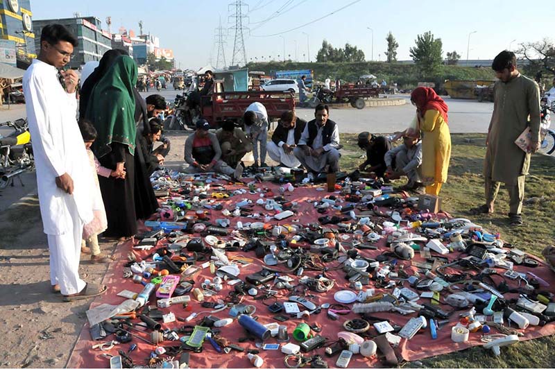 People purchasing used items from a roadside vendor at Khanna Pull