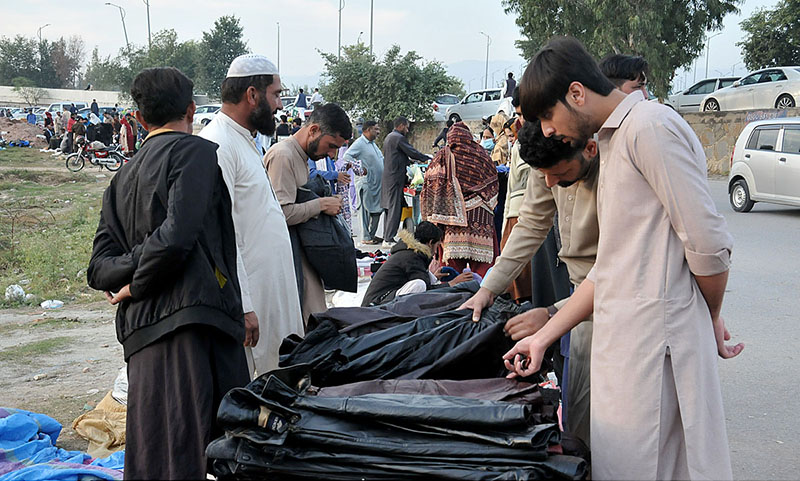 Customers are busy in selecting and purchasing second hand imported warm clothes from roadside vendor