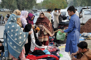 Customers are busy in selecting and purchasing second hand imported warm clothes from roadside vendor