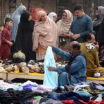People selecting and purchasing secondhand shoes and clothes from vendors