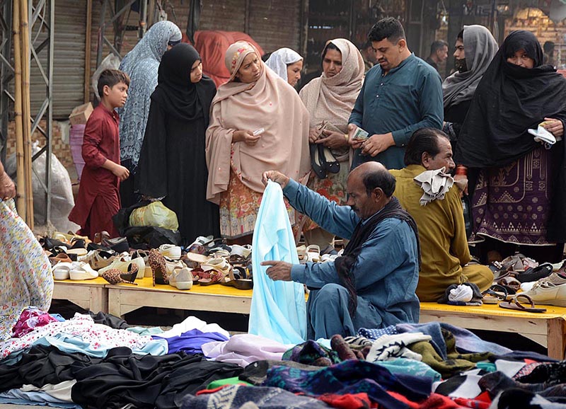 People selecting and purchasing secondhand shoes and clothes from vendors