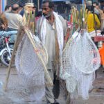 A vendor selling bird and fish catching nets to attract customers while shuttling at Ali Chowk Road