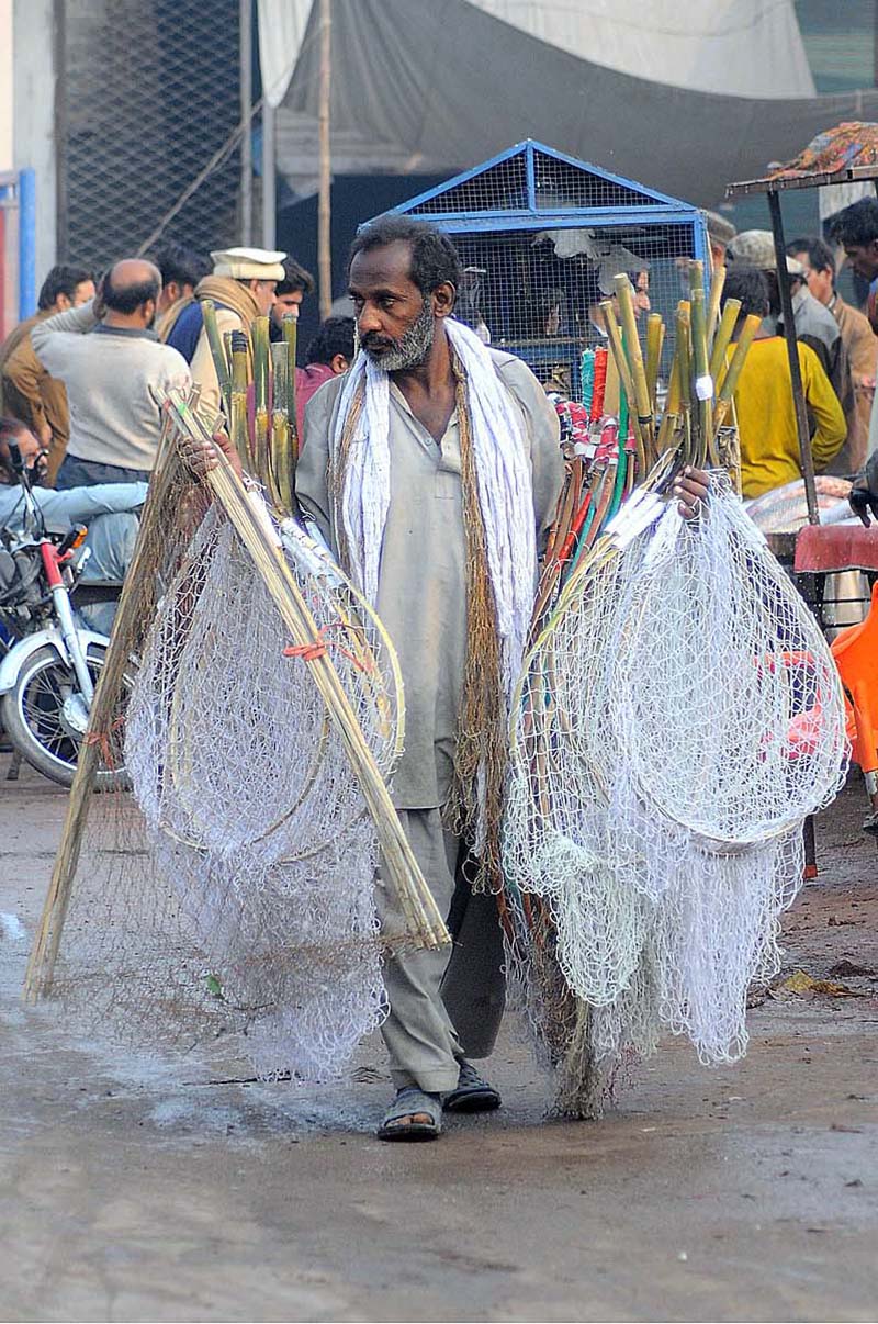 A vendor selling bird and fish catching nets to attract customers while shuttling at Ali Chowk Road