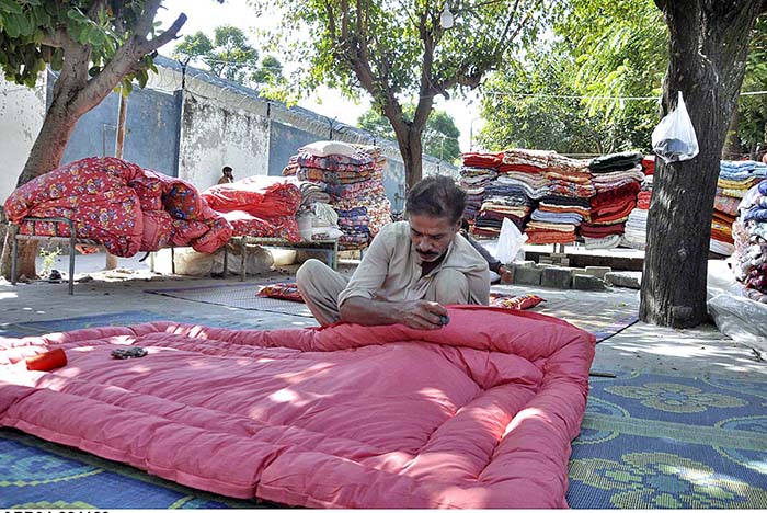 A worker busy in stitching quilt for customers at his workplace in Federal Capital.