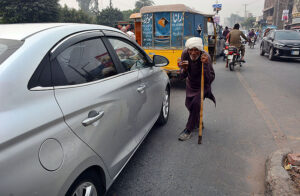 An old gypsy asking for some money from vehicle drivers at Jaranwala Road.