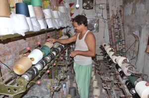 A power loom worker busy in routine work to earn livelihood at his workplace.