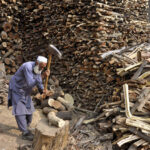 Old man cutting wood into pieces for selling purpose at his workplace in the Federal Capital.