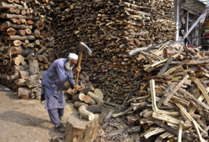 Old man cutting wood into pieces for selling purpose at his workplace in the Federal Capital.