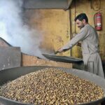 A worker busy in roasting grams at his workplace in local market.