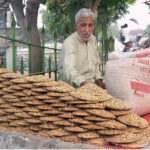 A vendor displaying pigeons food to attract customers at his roadside setup